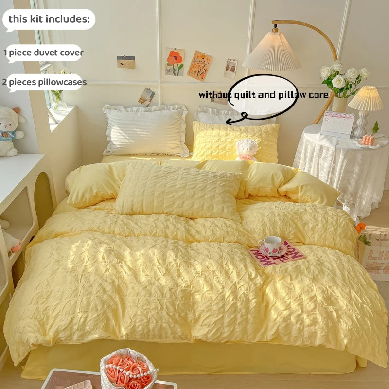 A yellow soft textured duvet cover set with pillowcases displayed on a bed, next to a lamp and flowers.