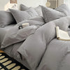 A close-up of a gray luxurious washed cotton bed linen set featuring pillows and a folded book on a bed.