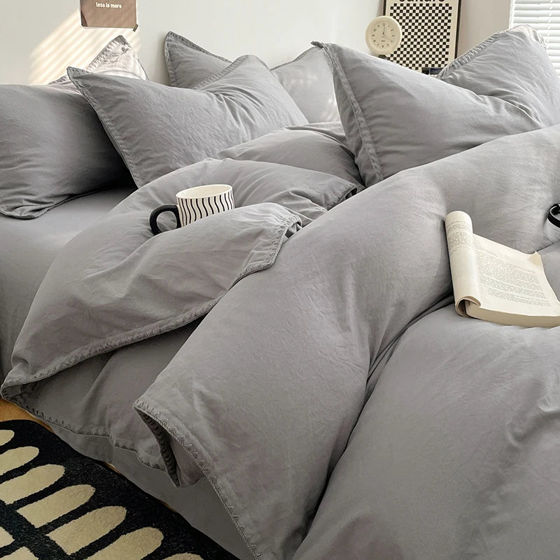 A close-up of a gray luxurious washed cotton bed linen set featuring pillows and a folded book on a bed.