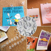 A collection of clear plastic push pins with steel tips pinned to colorful cards and a string of similar pins.