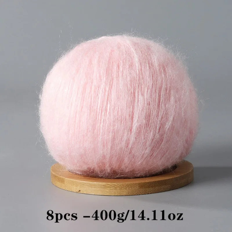 A spherical ball of pink mohair yarn used for crafting.