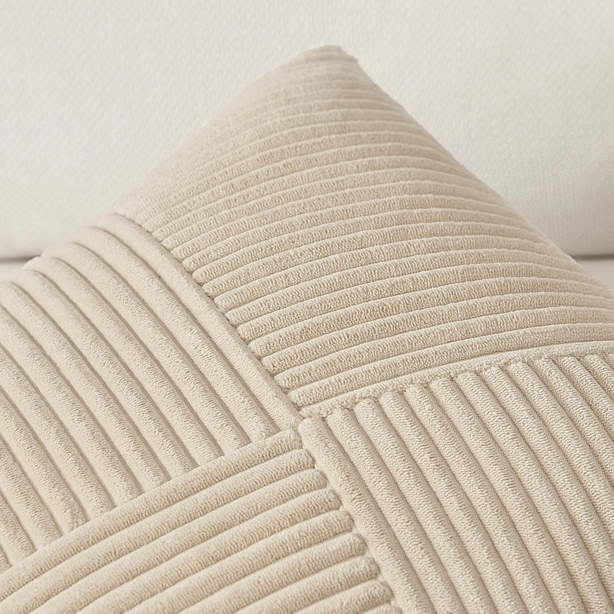 A close-up of a beige textured corduroy throw pillow cover with vertical ribbing.