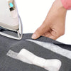A hand is applying iron-on fusible hem tape to a piece of dark gray fabric for DIY sewing.