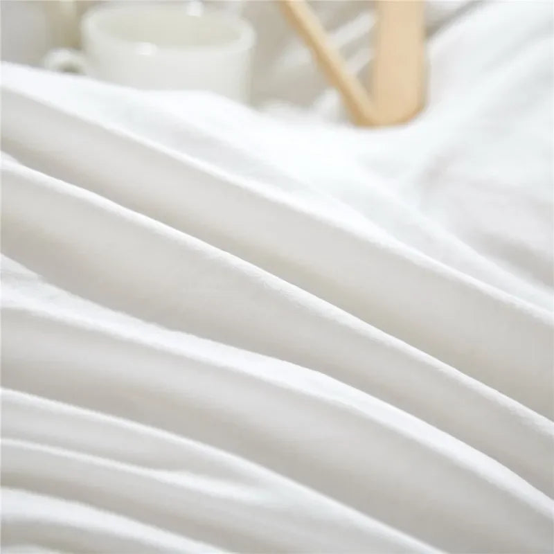 Close-up of a white soft washed duvet cover set with pom-pom decoration on white bedding.