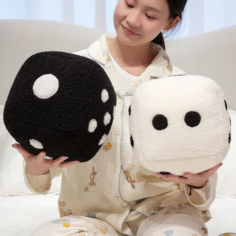 A woman holds a black and white oversized dice plush throw pillow in her hands.