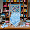 A collection of blue and white floral dot pattern cotton fabric squares laid out on a wooden table.