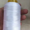 A spool of white high tenacity polyester sewing thread is held in a hand against a light background.