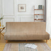 A beige velvet non-slip armless sofa cover displayed on a wooden floor with an open book.