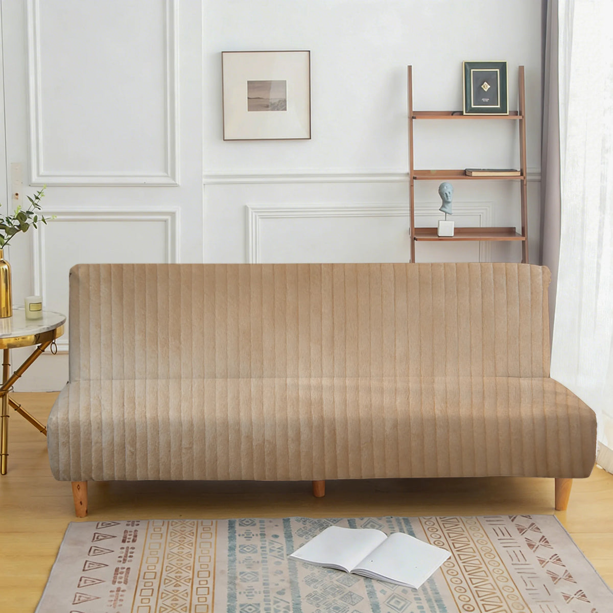 A beige velvet non-slip armless sofa cover displayed on a wooden floor with an open book.
