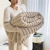A woman wearing a beige ultra-soft plush winter blanket with a textured, knitted appearance.