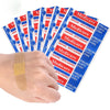 A hand holds a pack of red and blue medicated adhesive first aid strips for wound care.