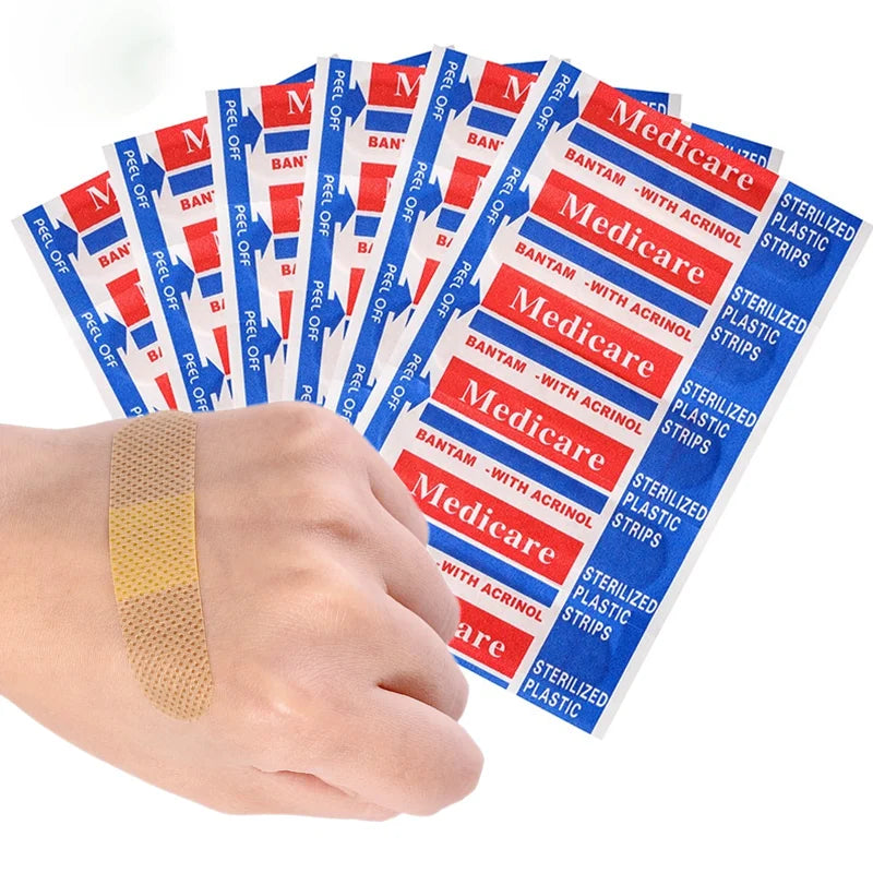 A hand holds a pack of red and blue medicated adhesive first aid strips for wound care.