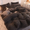 A dark gray plush mink velvet duvet set with matching pillows and a white accent pillow.