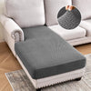 A gray jacquard stretch sofa cushion cover placed on a light-colored sofa and a rug.