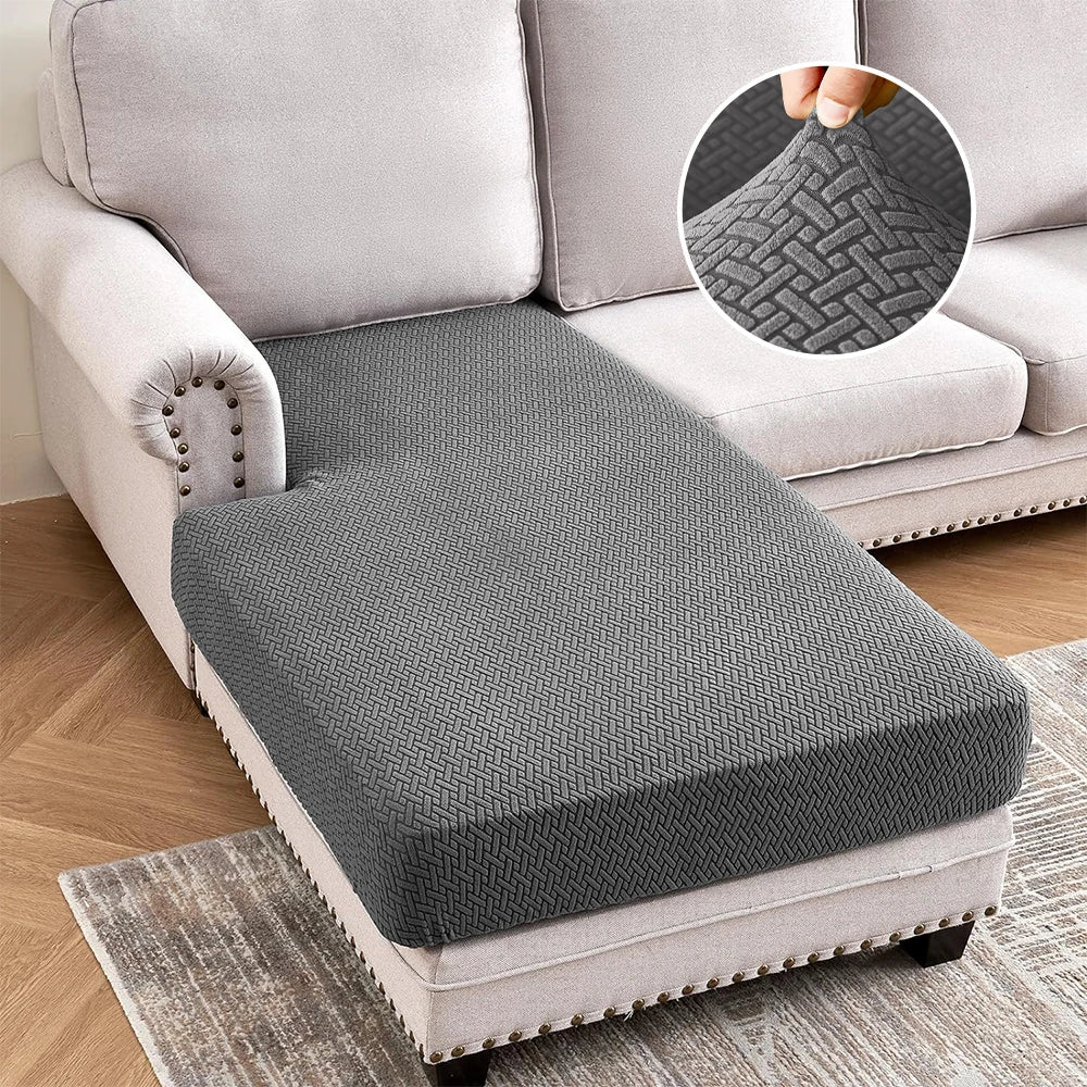 A gray jacquard stretch sofa cushion cover placed on a light-colored sofa and a rug.