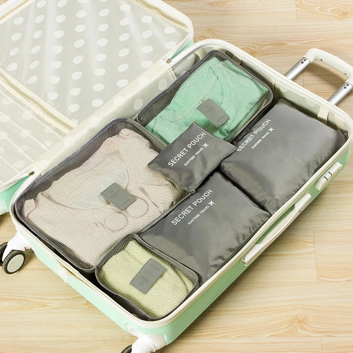 A light green travel organizer case containing six zippered pouches for travel storage.