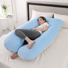 A woman rests on a light blue U-shaped maternity body pillow on a white bed.
