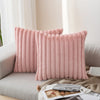 Two pink plush striped decorative pillowcases standing upright on a light-colored sofa.