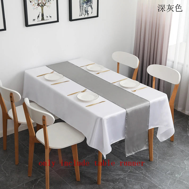 A white satin table runner with a gray accent is displayed on a long table set for an event.