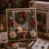 A vintage Christmas fabric art kit featuring a framed wreath and holiday decorations on a wooden surface.