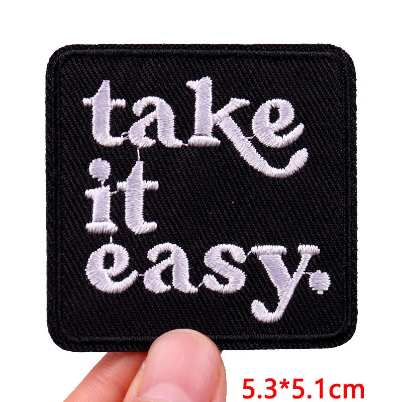 Black embroidered patch with white text that reads take it it easy