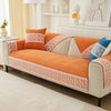An orange quilted sofa cover with white lace trim and neutral fabric cushions displayed on a light-colored sofa.