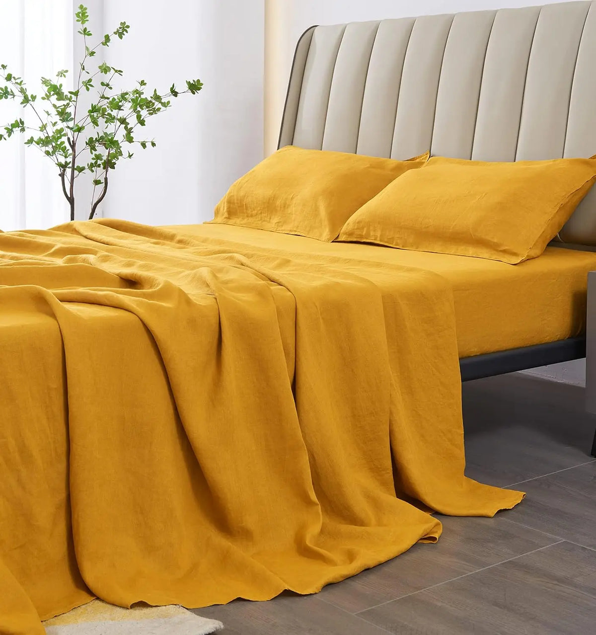 A mustard yellow linen bedding set featuring a headboard and draped fabric on a bed.