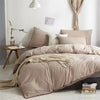 A beige duvet cover set with pom-pom decoration displayed on a bed in a bright room.