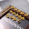 A collection of gold-toned metal pin findings including clasps and tie tacks arranged on a dark wooden surface.