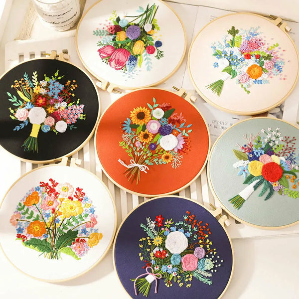 A collection of floral cross stitch embroidery kits featuring colorful fabric designs on round wooden boards.