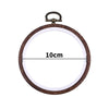 Round wooden embroidery hoop with a light-colored center and a brass-colored metal clamp.