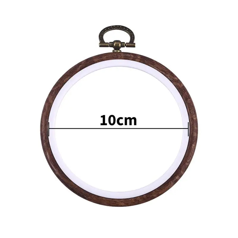 Round wooden embroidery hoop with a light-colored center and a brass-colored metal clamp.