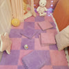 A purple and pink play mat with square tiles, a white stuffed animal, and a yellow ball in a soft room setting.