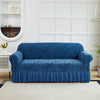 A deep blue anti-slip jacquard sofa slipcover placed on a light rug in a bright room.