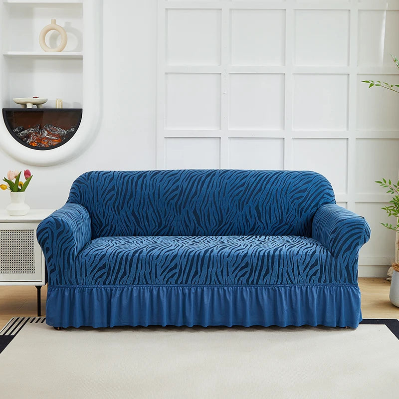 A deep blue anti-slip jacquard sofa slipcover placed on a light rug in a bright room.