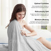 A woman is relaxing while draped in a light gray, breathable fabric blanket.