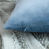 A close-up of a soft blue velvet decorative pillow cover resting on a knitted gray fabric.