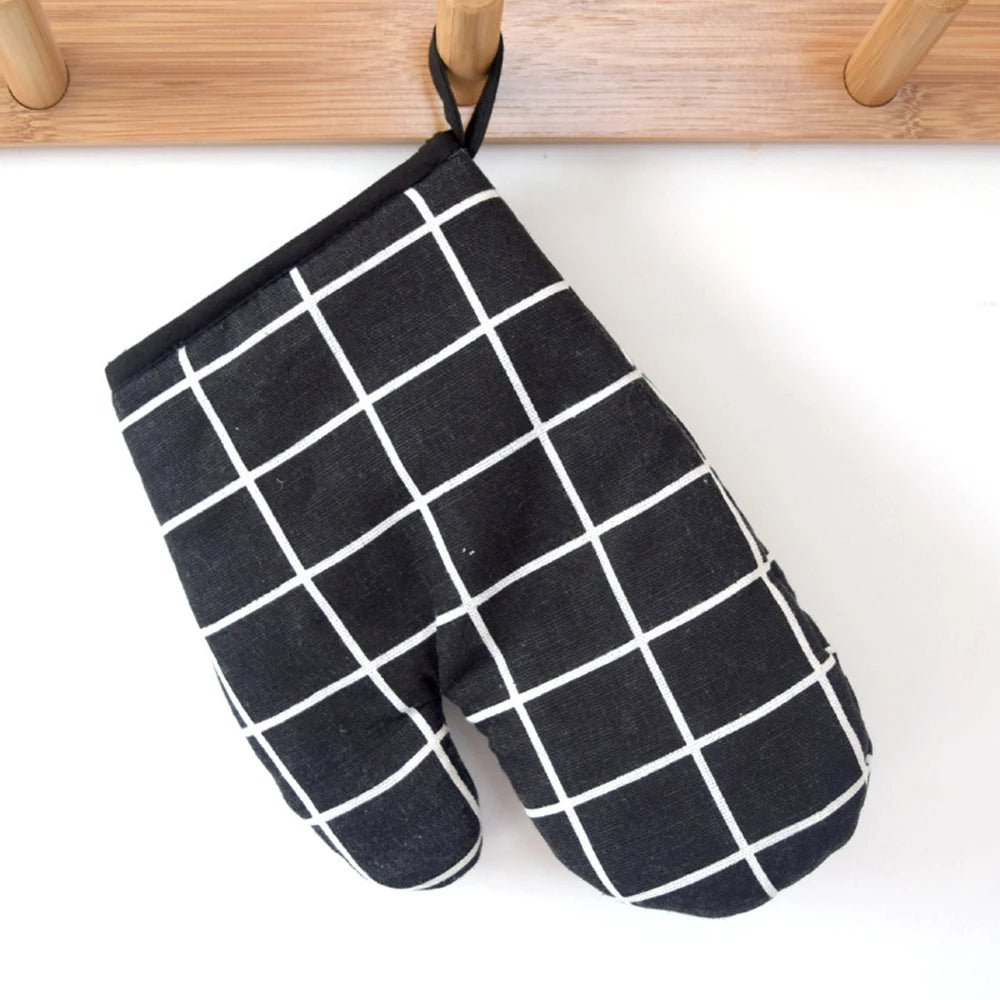 A pair of black and white checkered heat-resistant kitchen oven gloves hanging on a wooden rack.