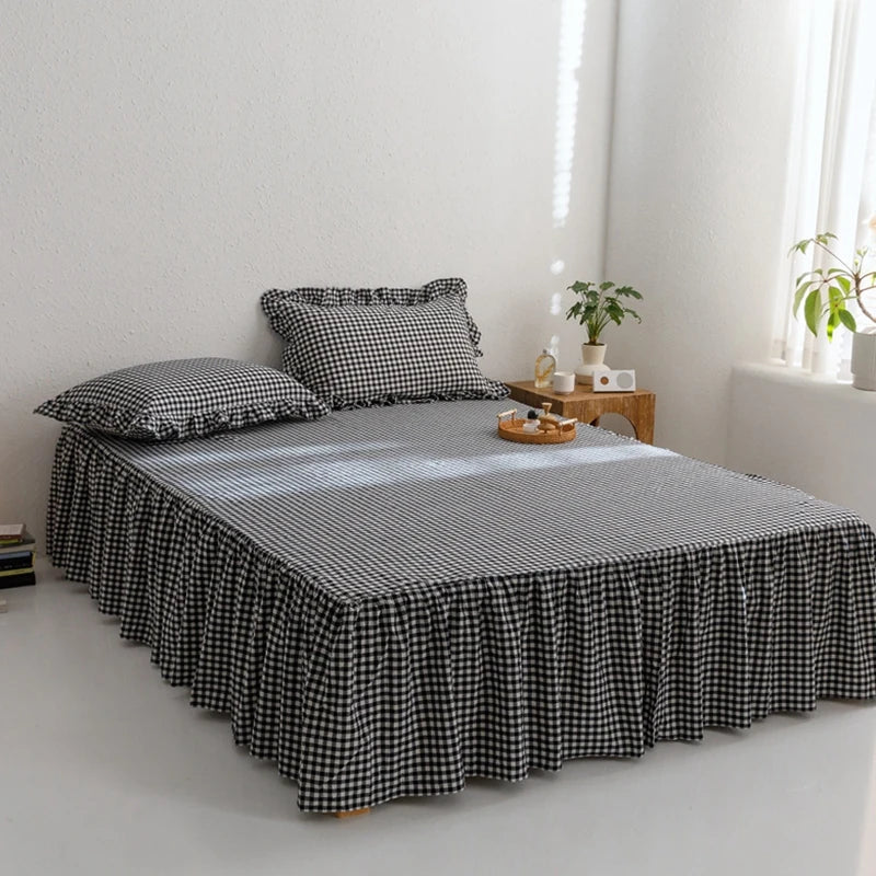 A black and white plaid cotton bed skirt cover draped over a bed in a bright room.