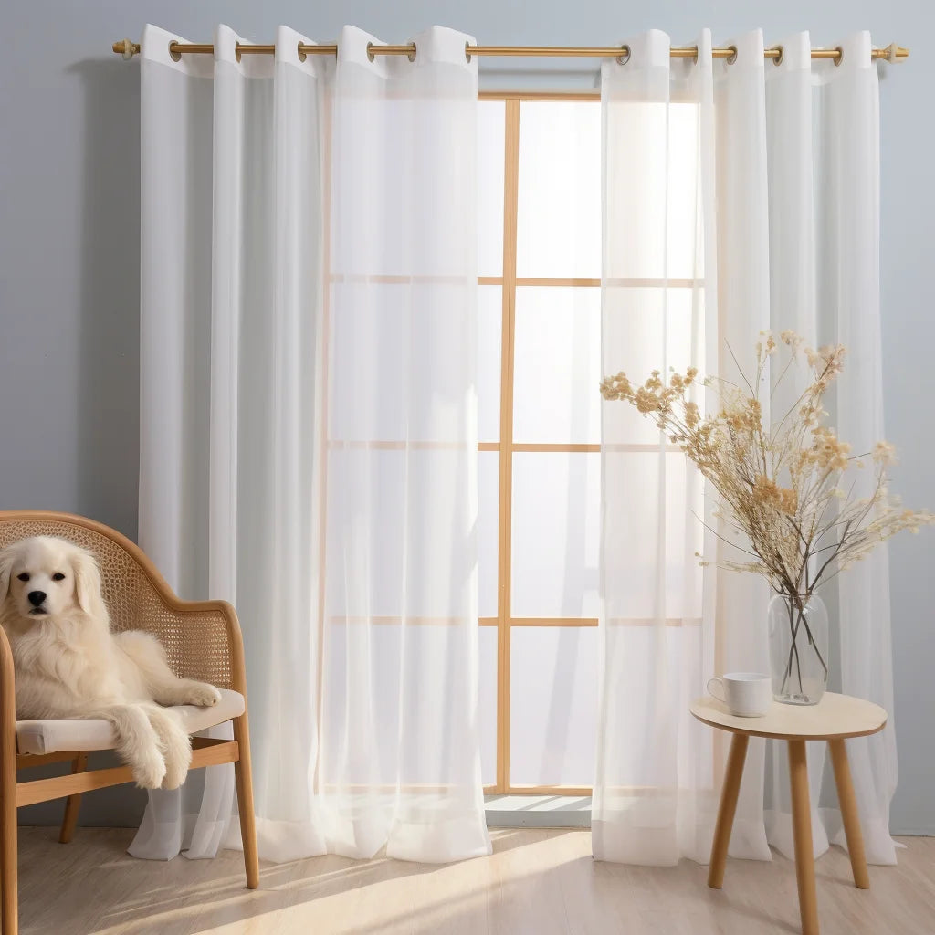 White sheer tulle window curtains hanging on a rod in a bright room with natural light.