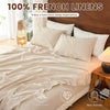 A bed dressed with 100% French linens featuring light beige and white pillows and bedding.