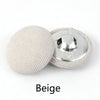 A beige round fabric-covered shank button is shown next to its silver metal base.