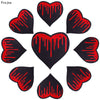 A collection of nine black heart-shaped embroidery patches with red dripping paint designs.