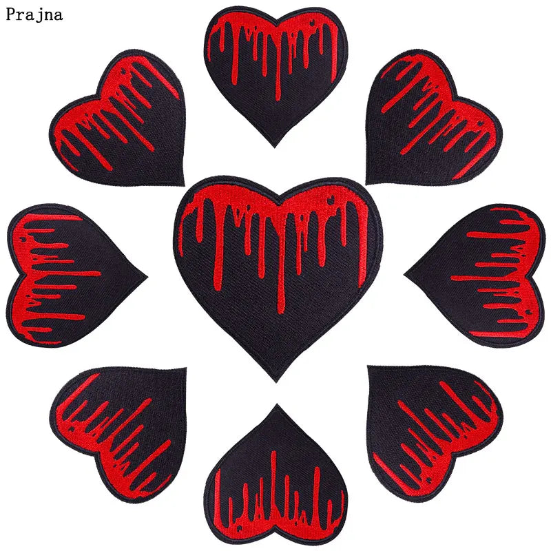 A collection of nine black heart-shaped embroidery patches with red dripping paint designs.