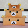 A set of three Rilakkuma plush bed pillows and sofa cushions in orange and cream colors.