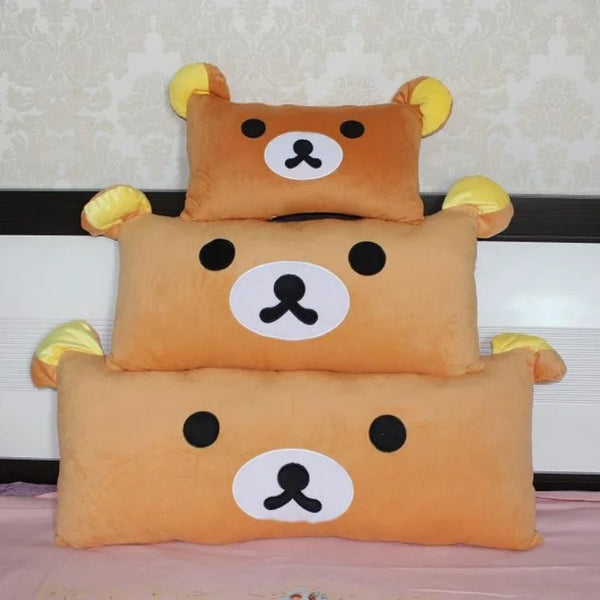 A set of three Rilakkuma plush bed pillows and sofa cushions in orange and cream colors.