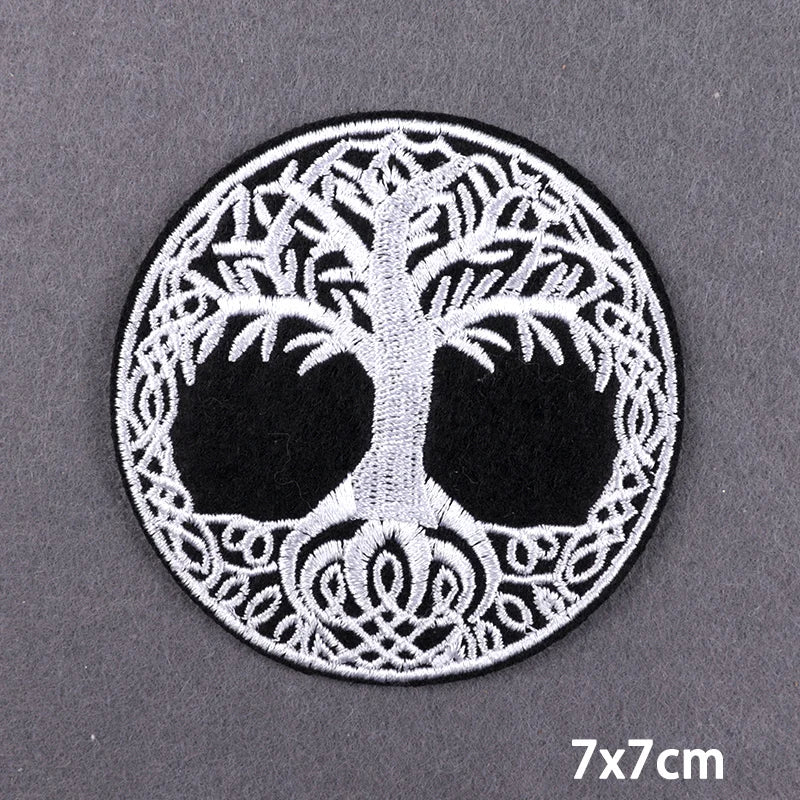 Black and white embroidered skull patch featuring intricate foliage design on a circular background
