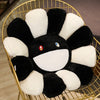 A black and white cozy sunflower plush cushion with a smiling face displayed in a gold wire basket.