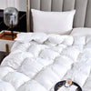 White luxury goose down quilt duvet with fluffy pillows on a bed