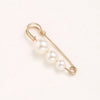 Gold-toned adjustable pearl brooch featuring a chain and three round pearls.